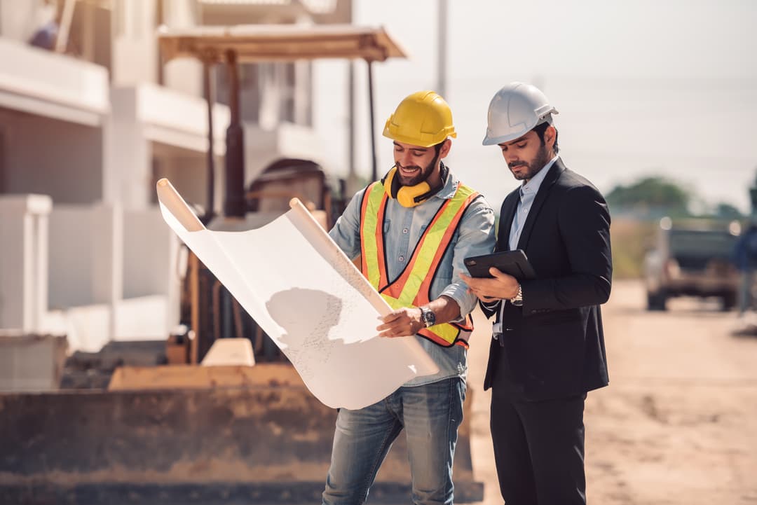 Construction workers reviewing blueprints at a building site
